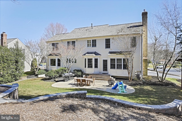 back of property with a yard, entry steps, a chimney, and a patio area