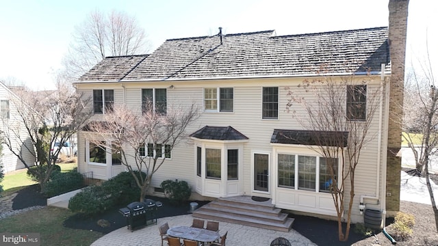 back of property with cooling unit, entry steps, a chimney, and a patio