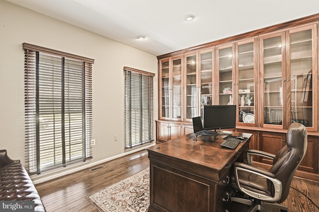 office featuring visible vents, plenty of natural light, dark wood-type flooring, and baseboards