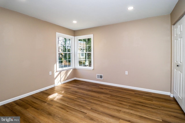 unfurnished room with wood finished floors, recessed lighting, baseboards, and visible vents