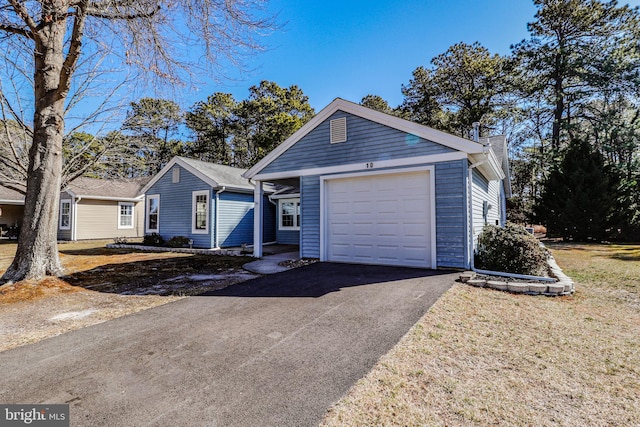 ranch-style home featuring aphalt driveway, a chimney, and a garage