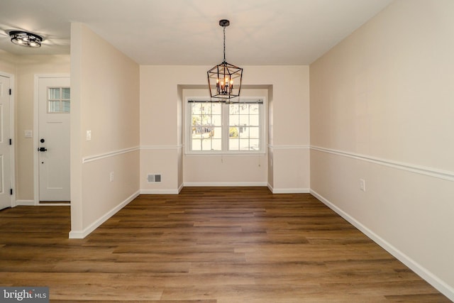 unfurnished dining area with visible vents, baseboards, a notable chandelier, and wood finished floors