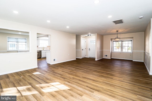 unfurnished living room with visible vents, light wood finished floors, baseboards, recessed lighting, and a notable chandelier