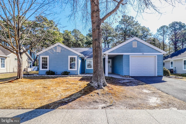 single story home featuring aphalt driveway, an attached garage, and a front yard