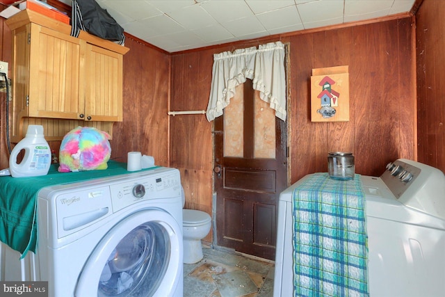 laundry room featuring laundry area, wood walls, and washing machine and dryer