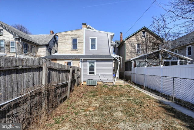 rear view of house featuring central AC and a fenced backyard