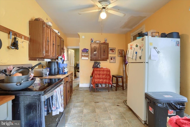 kitchen with electric stove, a ceiling fan, brown cabinets, and freestanding refrigerator