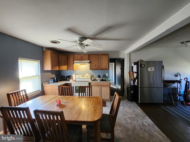 interior space with visible vents, white range with electric cooktop, freestanding refrigerator, light countertops, and under cabinet range hood