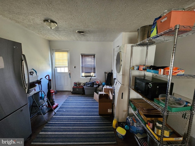 washroom featuring laundry area, visible vents, stacked washer / drying machine, and a textured ceiling