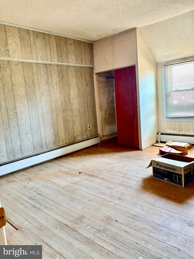 unfurnished bedroom featuring a textured ceiling, wood-type flooring, and a baseboard radiator