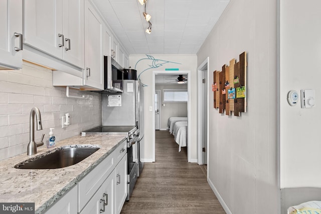 kitchen with backsplash, white cabinets, appliances with stainless steel finishes, and a sink