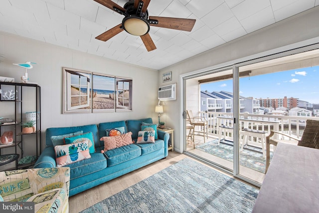 living room with ornamental molding, a ceiling fan, a wall unit AC, and wood finished floors