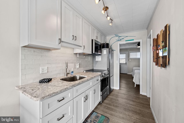 kitchen with decorative backsplash, appliances with stainless steel finishes, wood finished floors, white cabinets, and a sink