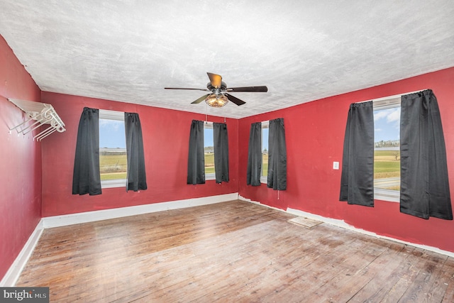 spare room with baseboards, a textured ceiling, wood finished floors, and a ceiling fan