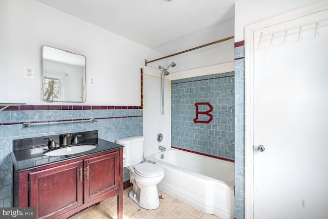 full bath with a wainscoted wall, toilet, shower / bath combination, vanity, and tile walls