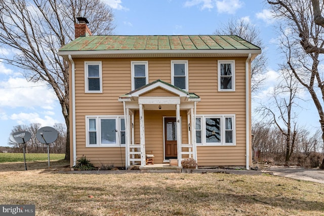 view of front of property featuring metal roof, a chimney, a front yard, and a standing seam roof