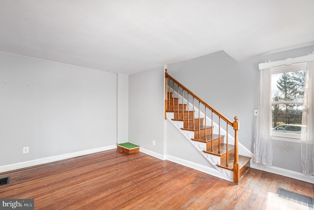 interior space with stairway, baseboards, visible vents, and hardwood / wood-style floors