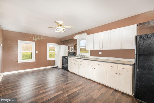 kitchen featuring black appliances, dark wood-type flooring, baseboards, white cabinetry, and a sink