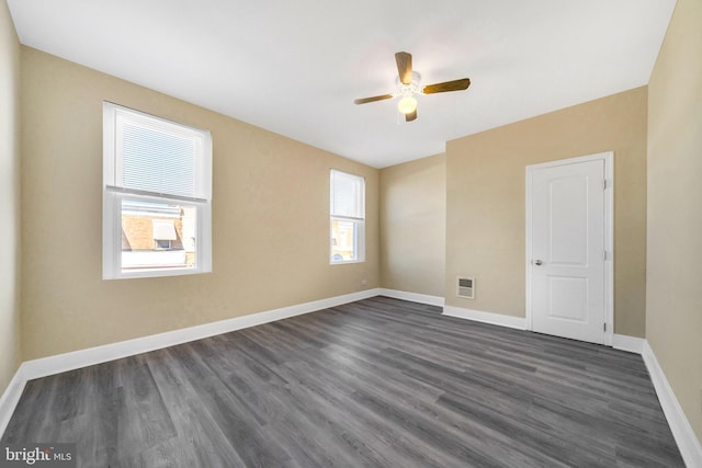 unfurnished room with visible vents, baseboards, dark wood-style floors, and a ceiling fan