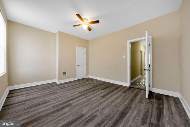 spare room with dark wood-style floors, visible vents, a ceiling fan, and baseboards