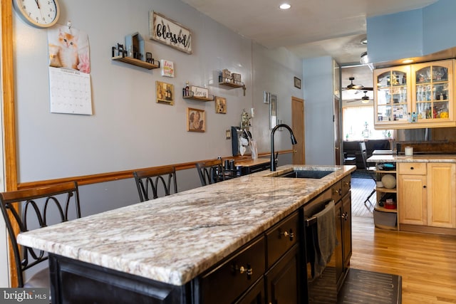 kitchen with a sink, light stone counters, light wood-style floors, a ceiling fan, and open shelves