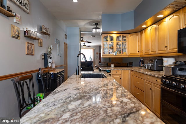 kitchen featuring a sink, light stone countertops, ceiling fan, and range with two ovens