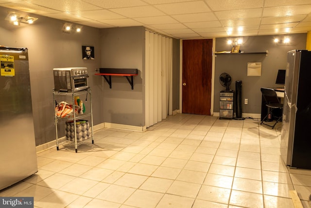 interior space featuring light tile patterned floors, a paneled ceiling, and baseboards