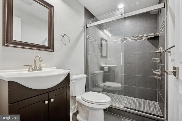 full bathroom featuring a stall shower, baseboards, toilet, and vanity