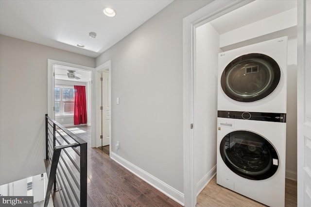 clothes washing area with wood finished floors, baseboards, laundry area, and stacked washer / drying machine