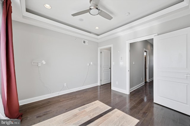 spare room featuring a tray ceiling, baseboards, wood finished floors, and a ceiling fan