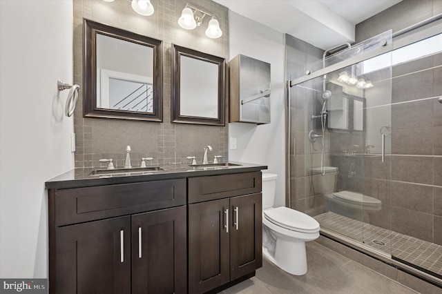 bathroom featuring a shower stall, toilet, decorative backsplash, and a sink