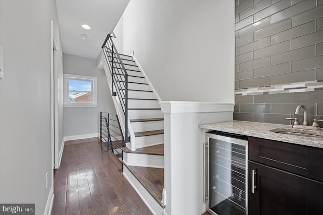 bar featuring decorative backsplash, baseboards, wet bar, a sink, and beverage cooler