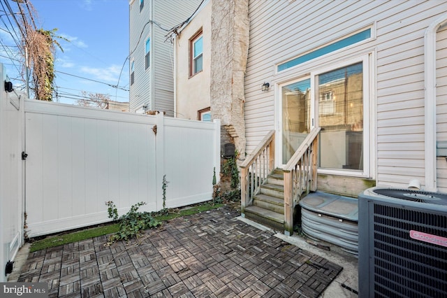 view of patio with central air condition unit, entry steps, and fence