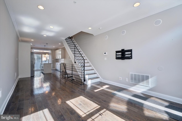 interior space featuring dark wood-style flooring, ornamental molding, baseboards, and visible vents