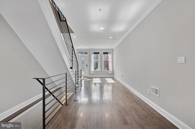 corridor with visible vents, baseboards, ornamental molding, wood finished floors, and recessed lighting