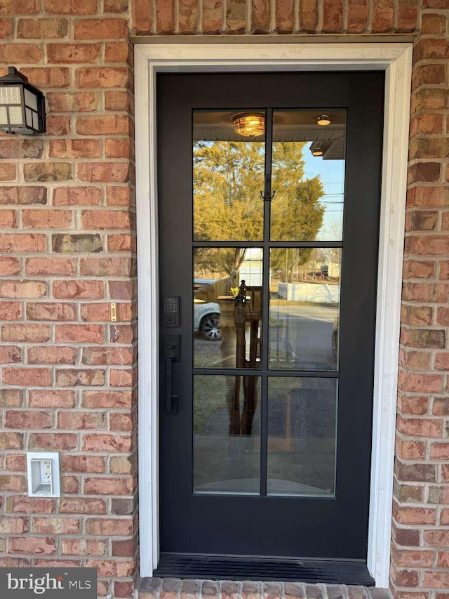 view of exterior entry featuring brick siding