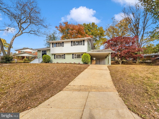 tri-level home featuring an attached carport, a front yard, and driveway