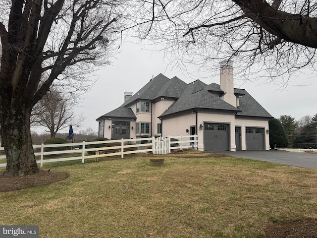 view of front of property with an attached garage, a chimney, a front lawn, and fence