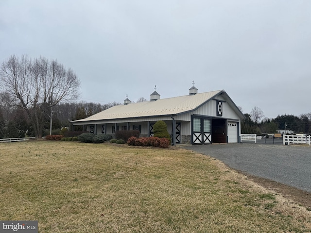 view of front of property featuring gravel driveway, a front lawn, fence, metal roof, and an outdoor structure