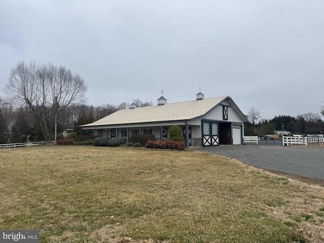 view of front of home featuring a front yard, fence, driveway, an attached garage, and metal roof