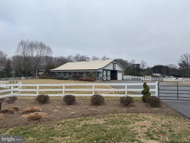 view of yard with a fenced front yard, a rural view, a garage, and driveway