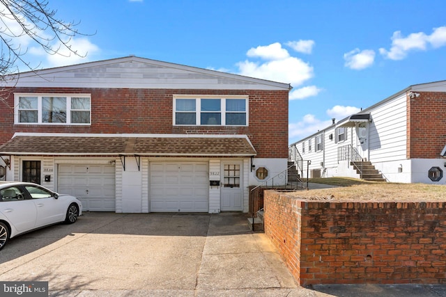 view of property featuring brick siding, concrete driveway, a garage, and roof with shingles