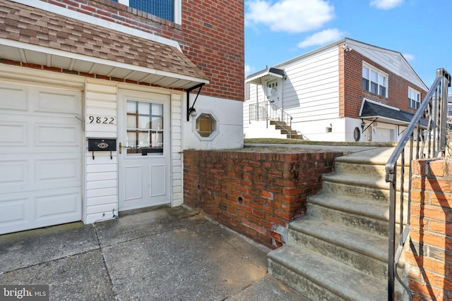 doorway to property featuring a garage and roof with shingles