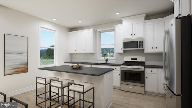 kitchen with dark countertops, a kitchen breakfast bar, appliances with stainless steel finishes, and a sink