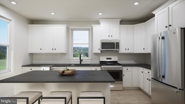 kitchen with dark countertops, stainless steel appliances, a breakfast bar, and a sink