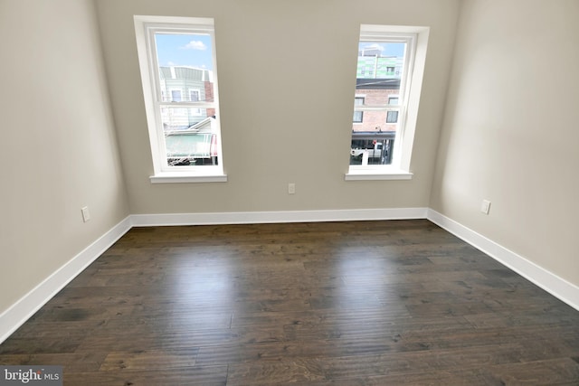 spare room with dark wood-type flooring and baseboards