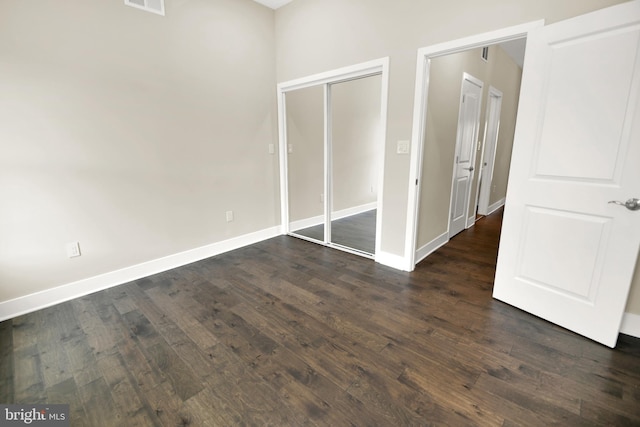 unfurnished bedroom featuring a closet, visible vents, baseboards, and dark wood-style flooring