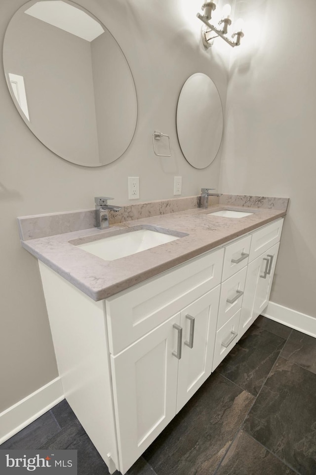 full bath featuring double vanity, baseboards, and a sink