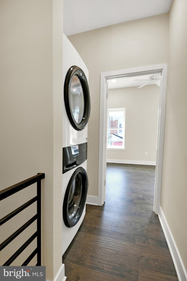 laundry room with stacked washer / drying machine, baseboards, dark wood finished floors, and laundry area