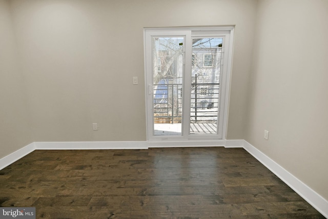 spare room featuring dark wood-type flooring and baseboards